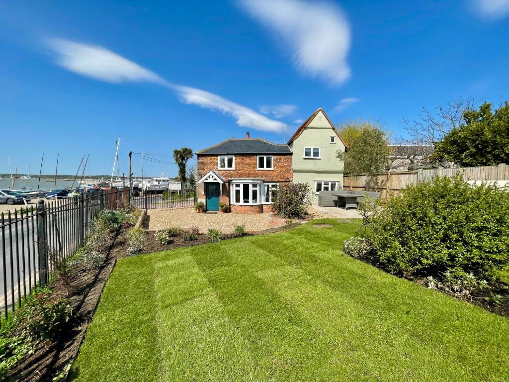 a house with a yard with a fence at Cosy Coastal 2-Bedroom Cottage with Hot Tub and Log Burner in West Mersea