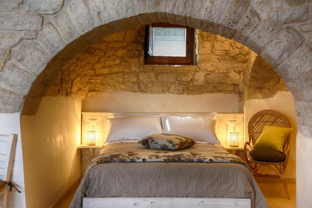 a bedroom with a large bed in a stone wall at Trullo Dell'Erba in Alberobello