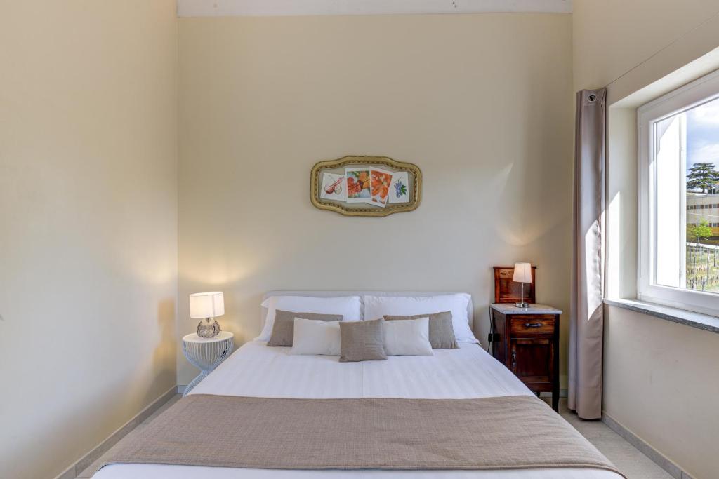 a white bed in a bedroom with a window at Ciabot delle Aie - Barolo in Barolo