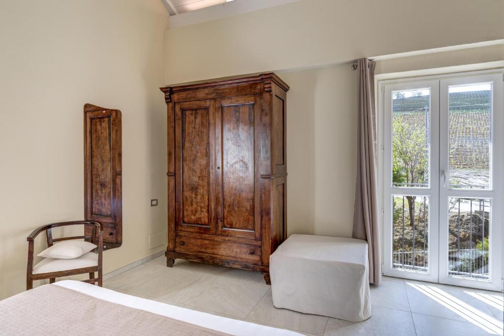 a bedroom with a wooden cabinet and a bed and a window at Ciabot delle Aie - Barolo in Barolo