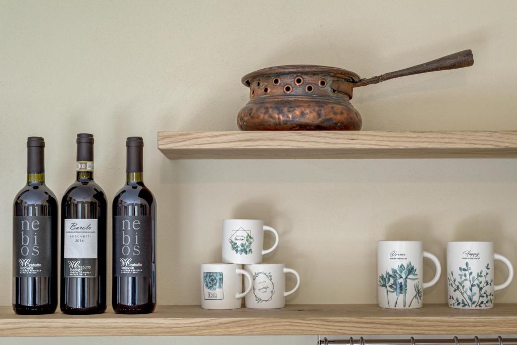 a shelf with three bottles of wine and mugs at Ciabot delle Aie - Barolo in Barolo