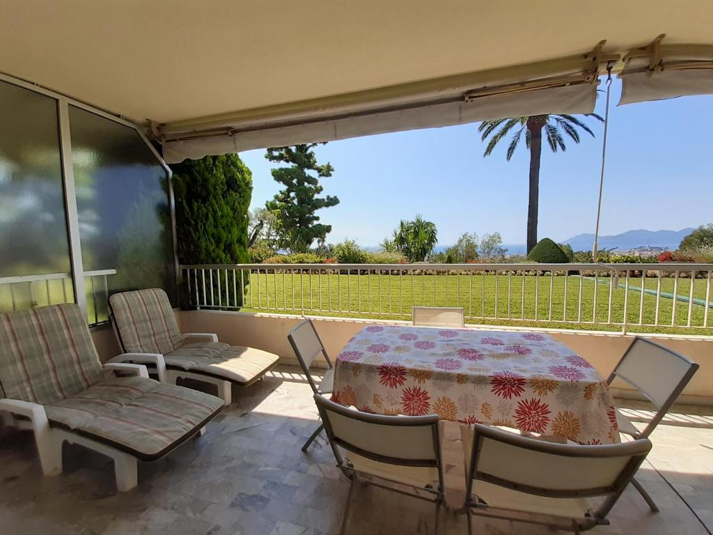 einen Tisch und Stühle auf einer Terrasse mit Blick auf eine Palme in der Unterkunft Le Renoir in Cannes