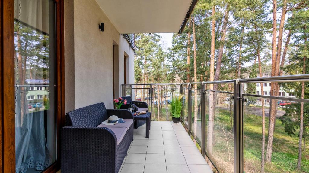 Balcony with rattan sofa and chairs, glass railing overlooking pine trees and courtyard