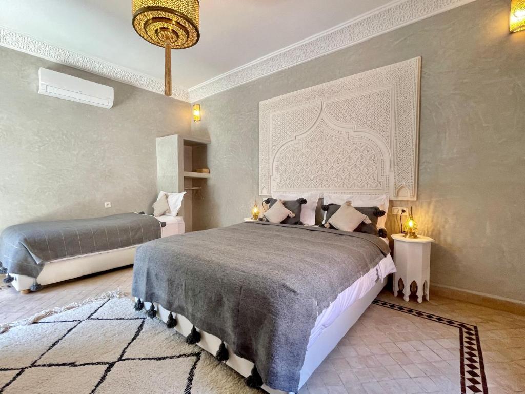 1 dormitorio con 2 camas y lámpara de araña en Riad Jolie en Marrakech