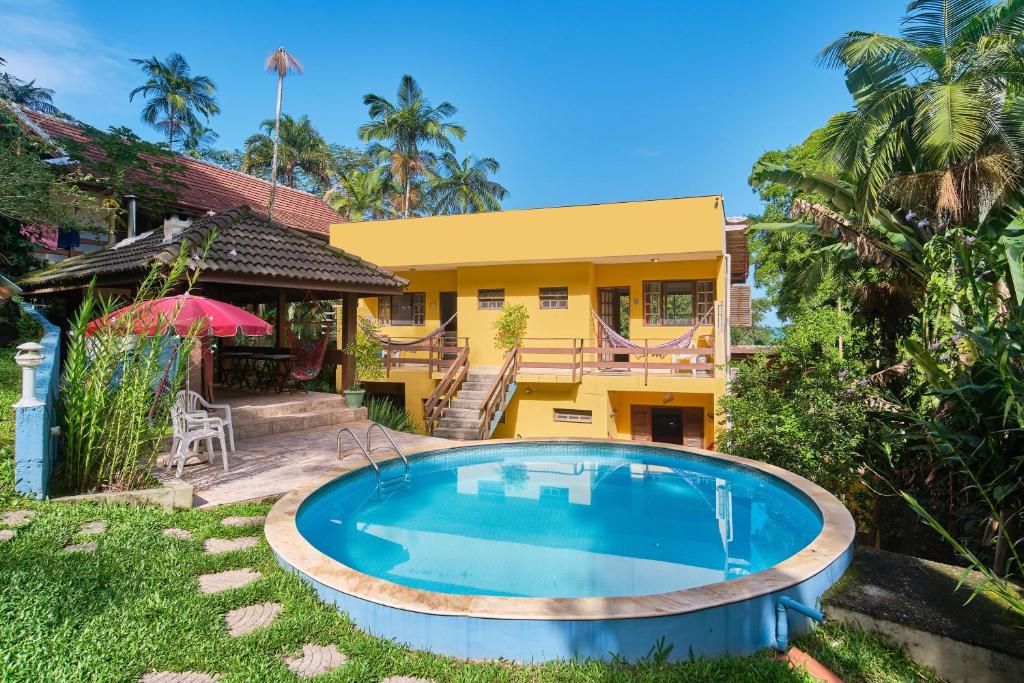 a villa with a swimming pool in front of a house at Studios na Vermelhinha in Ubatuba