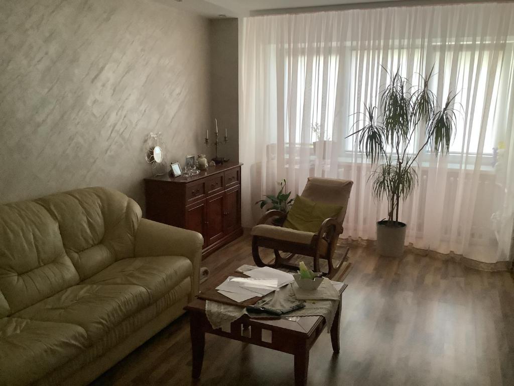 een woonkamer met een bank en een tafel bij Comfortable apartmnent in Narva with breakfast in Narva