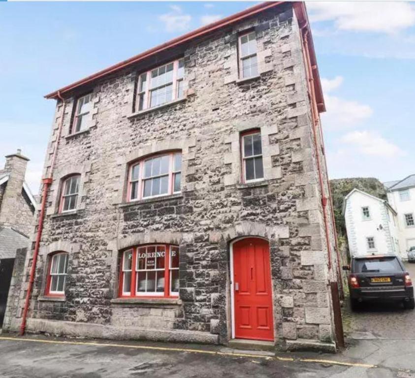 un ancien bâtiment en briques avec une porte rouge dans l'établissement Large heritage-House close Snowdonia & Llandudno, à Denbigh