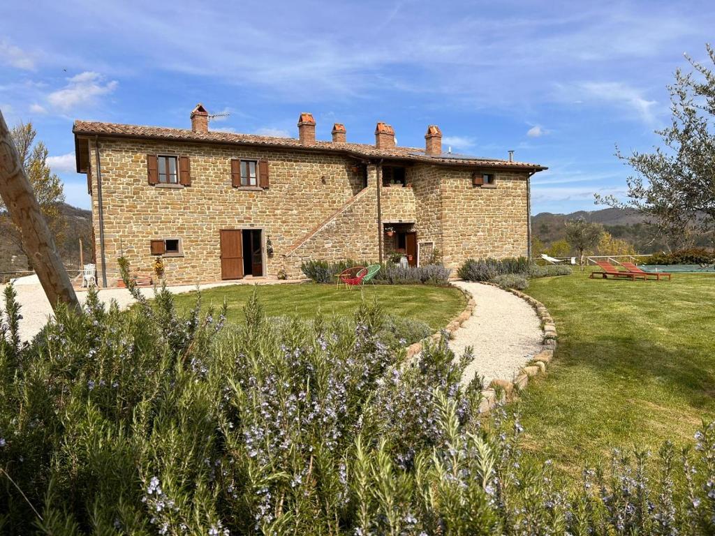 una vecchia casa in pietra con un sentiero che la porta di Villa Convento Pietralunga a Pietralunga