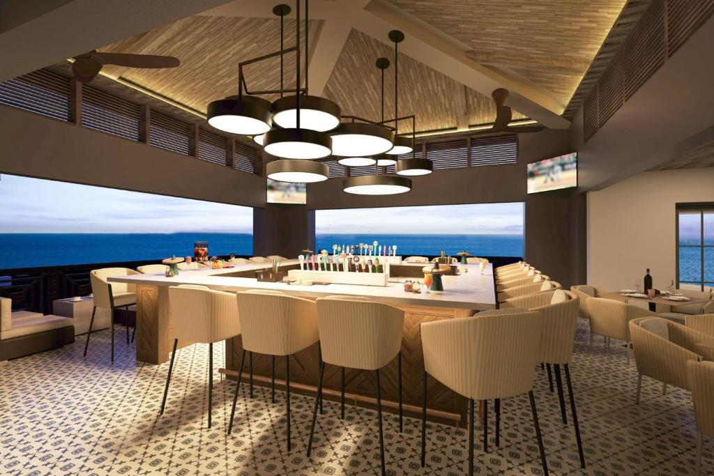 a restaurant with a bar with a view of the ocean at Hotel Indigo - Panama City Marina by IHG in Panama City
