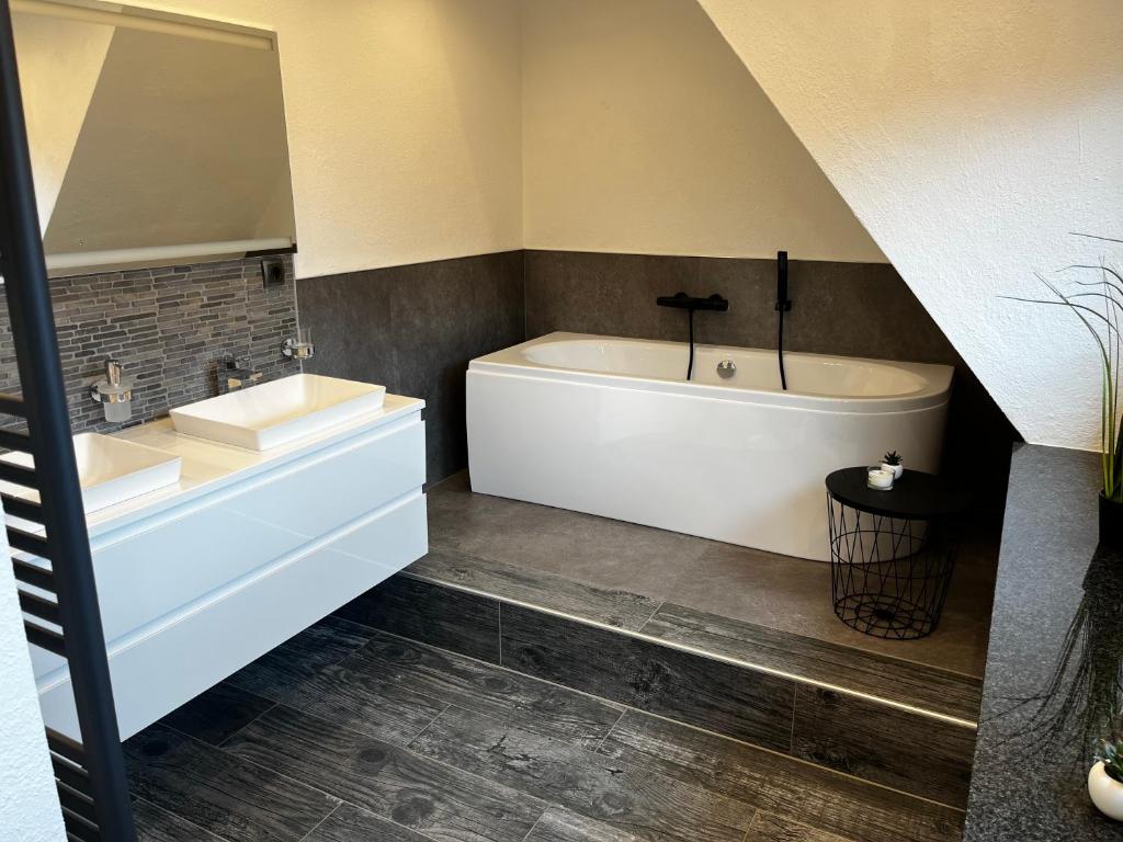 a bathroom with a white tub and a sink at Ferienwohnung am See Dillich - Schwimmteich - Eigener Garten - Ruhige Lage - Hunde willkommen in Borken