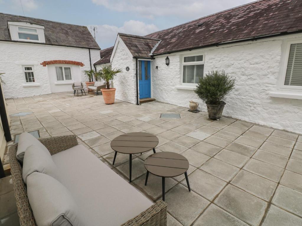 un patio con sofá, mesas y una casa en Bluebell Cottage, en Tenby