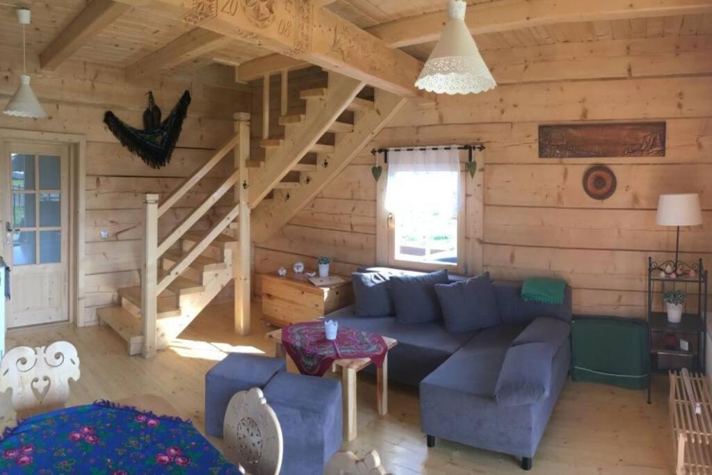 sala de estar con sofá azul y escalera en Osada Koniówka Domek D, en Koniówka