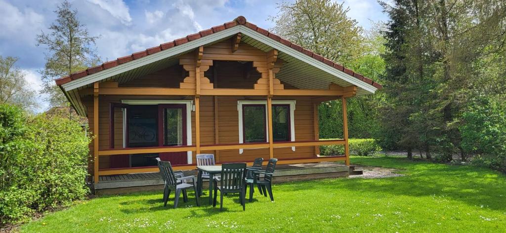 eine kleine Hütte mit einem Tisch und Stühlen im Gras in der Unterkunft Familie bungalow Sundsvall in Gramsbergen