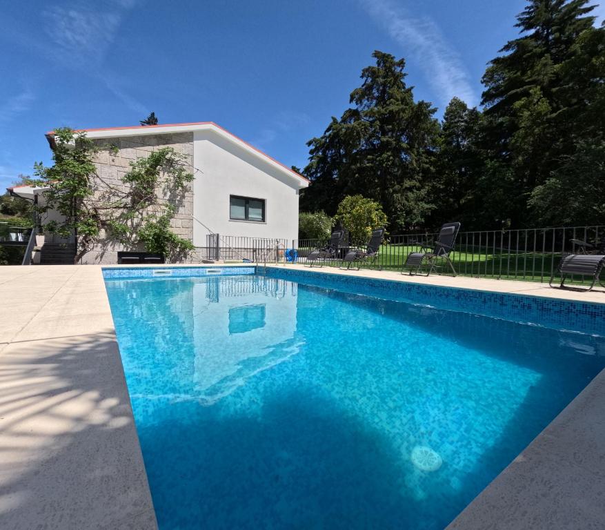 a swimming pool with blue water in front of a house at Casa de Pinheiral in Baião