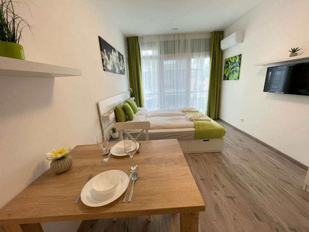 a room with a bed and a wooden table in a room at Siesta Apartman in Balatonberény