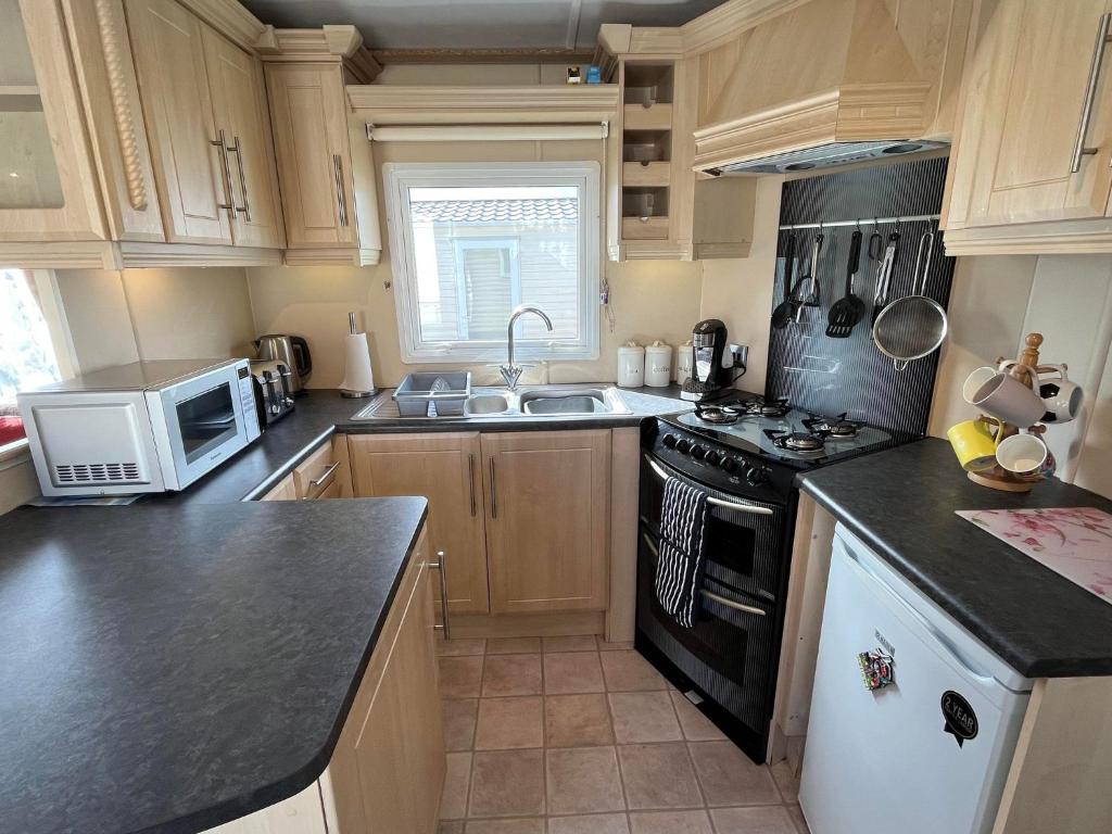 a kitchen with a stove and a microwave at Eagle 63, Scratby - California Cliffs, Parkdean, sleeps 6, pet friendly, bed linen and towels included - close to the beach in Scratby