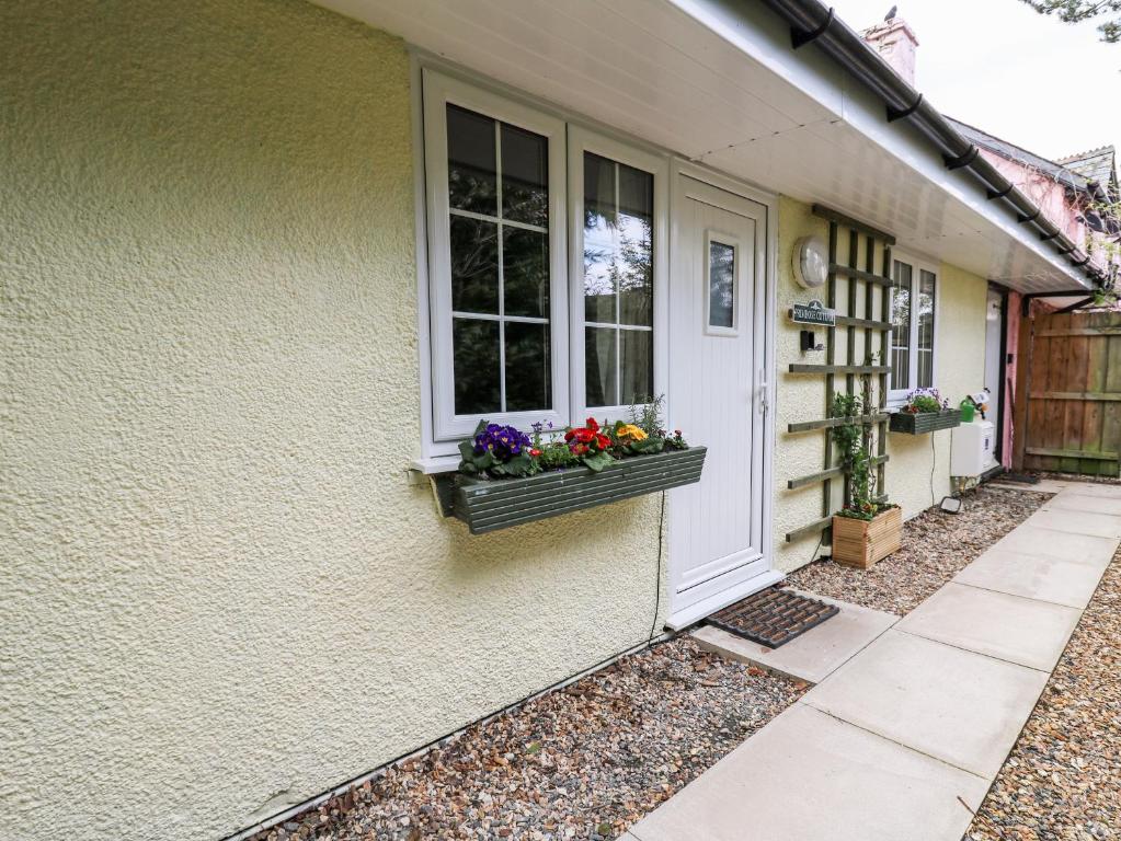 Primrose Cottage في لاندرندود ويلز: منزل مع نافذة مع الزهور في صندوق النافذة
