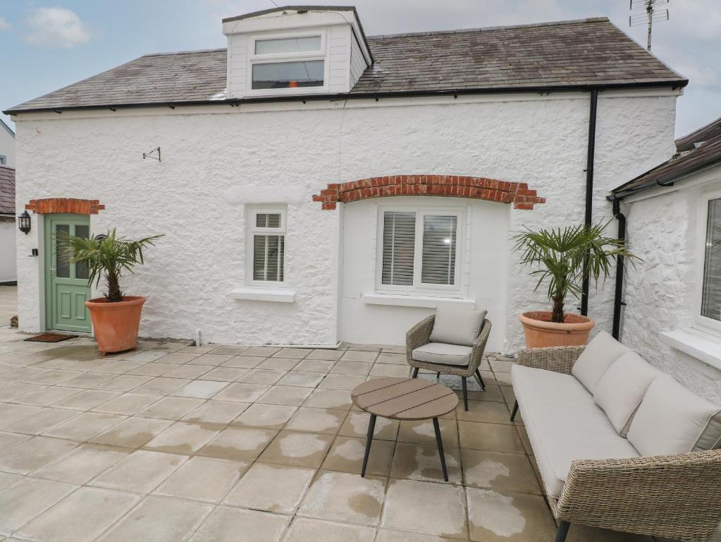 un patio con sofá, mesa y casa en Rosemary Cottage, en Tenby