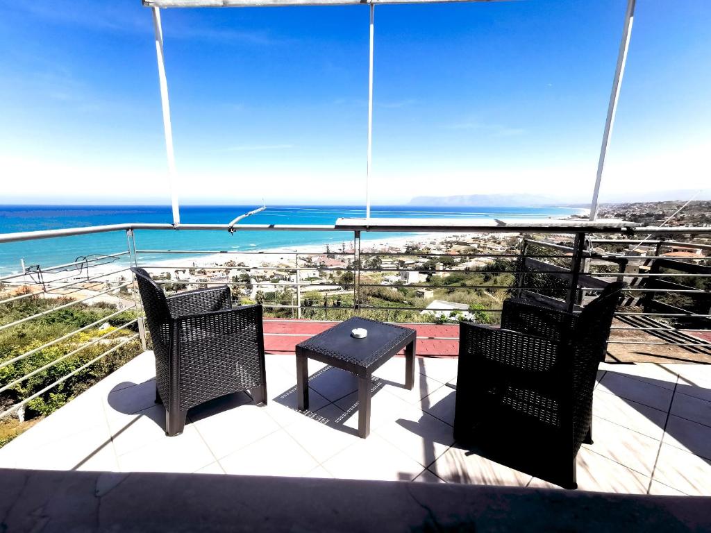 un patio con 2 sillas, una mesa y el océano en Terrazze sul golfo apartments en Castellammare del Golfo