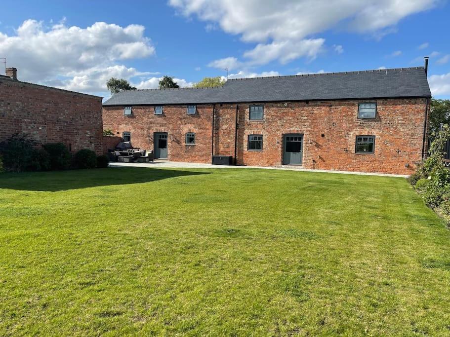 an old brick building with a large grass yard at Luxury Barn Conversion Perfect for Family Getaways in Foggathorpe
