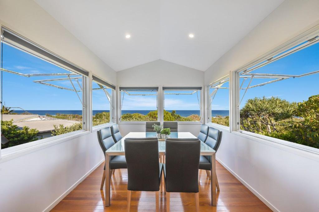 a dining room with windows and a table and chairs at 2 6 Teal Street Peregian Beach in Peregian Beach