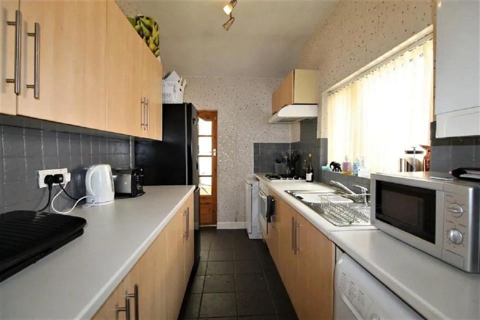a kitchen with wooden cabinets and a white counter top at 50 Adelaide Road Stockport sk3 9lp in Stockport