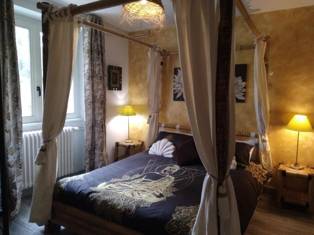 1 dormitorio con cama con dosel y cortinas en Gîte "Les Bambous" 6 personnes, prestations bien-être, salle et aire de jeux enfants, en Allègre