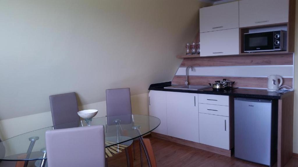 uma cozinha com uma mesa de vidro e armários brancos em Apartament z widokiem na góry em Ząb