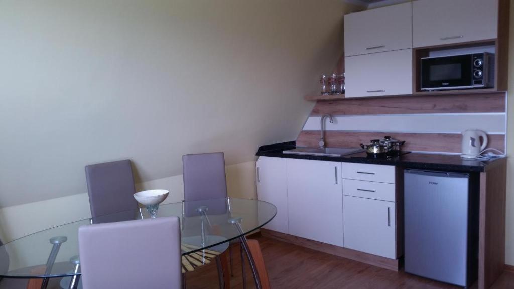 a kitchen with a glass table and white cabinets at Apartament z widokiem na góry in Ząb