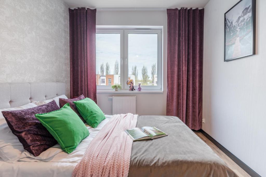 sypialnia z łóżkiem z zielonymi poduszkami i oknem w obiekcie Platinum Premium Apartment w Grudziądzu