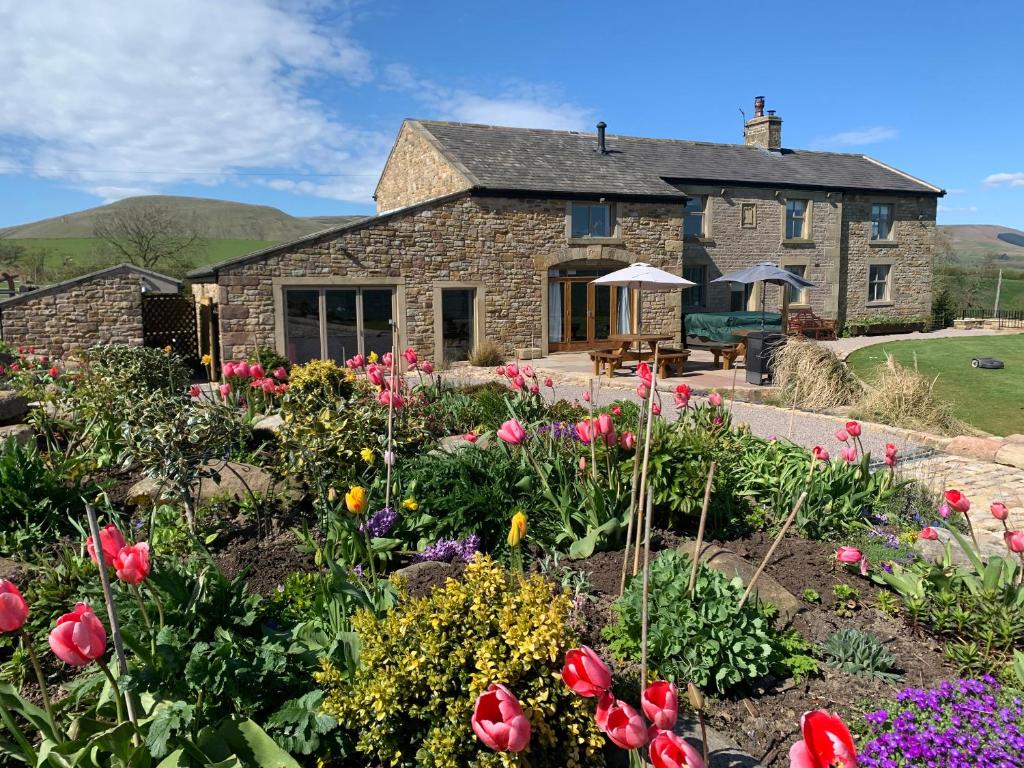 a stone house with flowers in front of it at Cuthbert Hill Farm in Preston