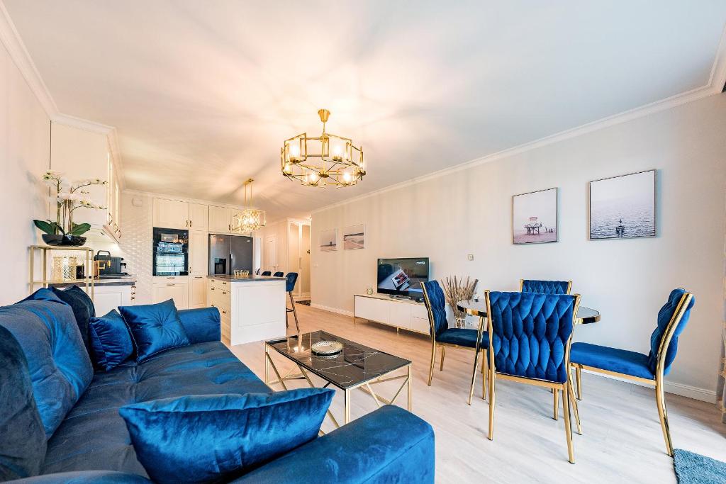 a living room with a blue couch and chairs at Nowa Letnica Apartament in Gdańsk