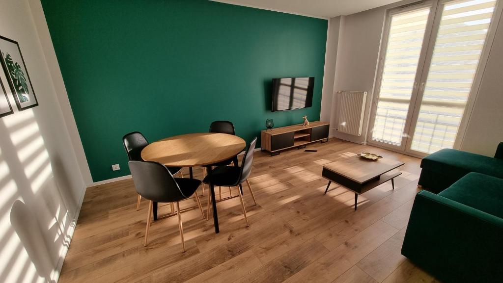 a living room with a table and chairs and a green wall at Apartament w Centrum in Częstochowa