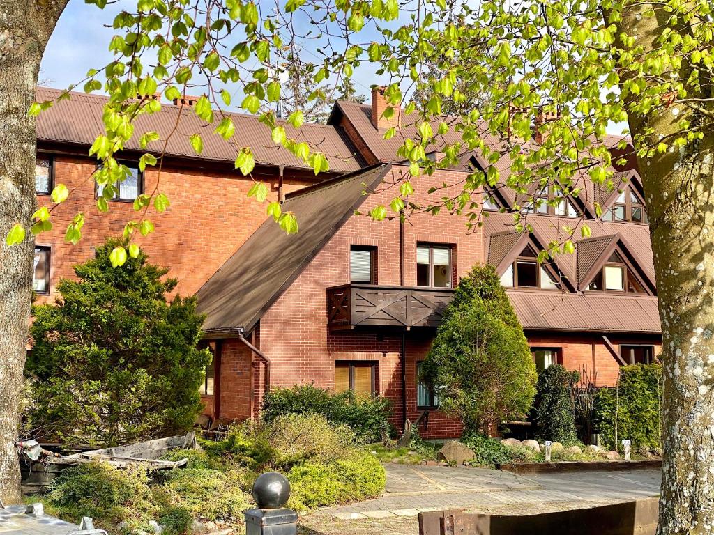 a large brick building with a black roof at Apartamenty Marea Rentals przy Promenadzie Słońca Poddąbie in Poddąbie