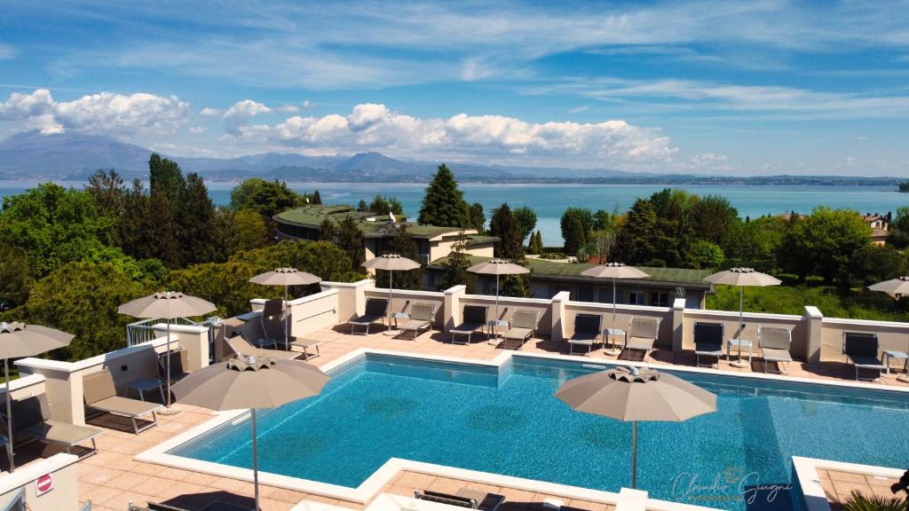 une grande piscine avec des parasols et l'océan dans l'établissement Hotel Alfieri, à Sirmione