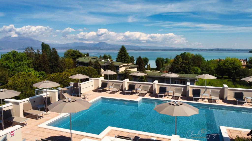a large swimming pool with umbrellas and the ocean at Hotel Alfieri in Sirmione
