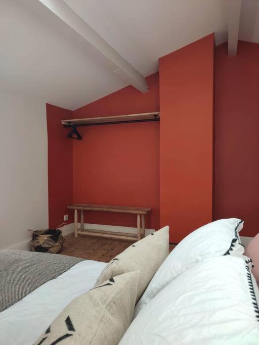 a bedroom with a red wall with a bed and a bench at Uzès médiévale l&#39;écrin d&#39;Amalia in Uzès