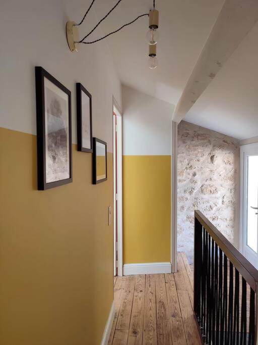 a hallway with yellow walls and a staircase with pictures on the wall at Uzès médiévale l&#39;écrin d&#39;Amalia in Uzès