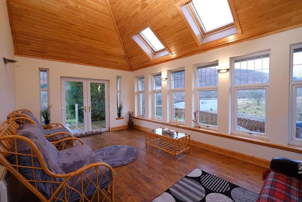 a large living room with windows and a wooden ceiling at Rowan Cottage Highland retreat near Fort William in Spean Bridge