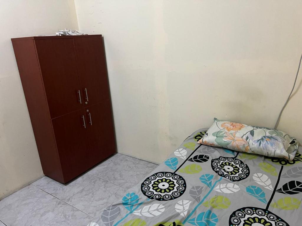 a small bedroom with a bed and a cabinet at comfortable homeroom for upto 2 persons in Sharjah