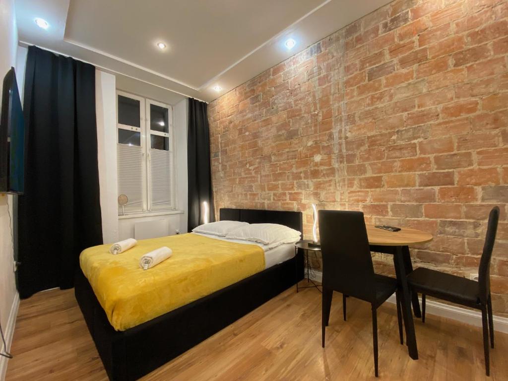 a bedroom with a bed and a brick wall at Central Rooms Apartment in Toruń
