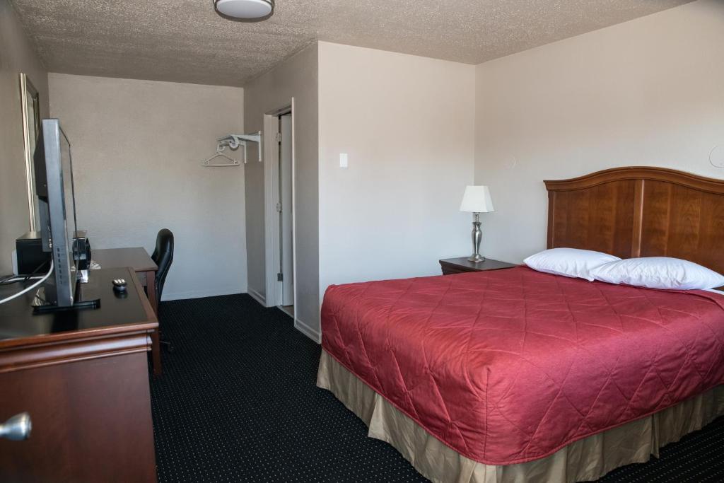 a hotel room with a bed with a red bedspread at Regency Inn in Springfield