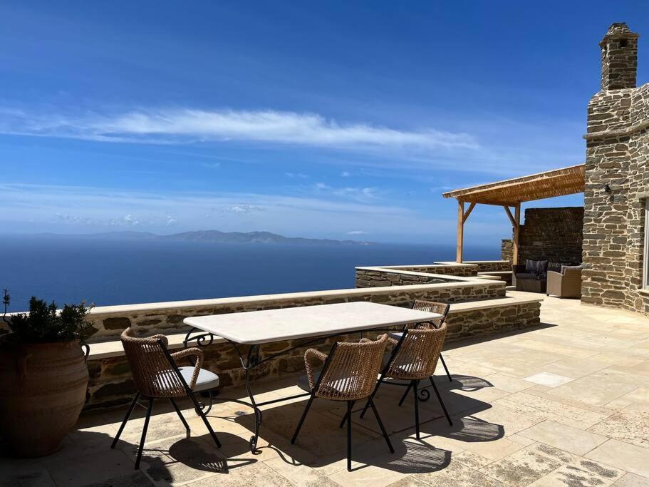 una mesa y sillas en un patio con vistas al océano en Villa Cybele Tinos, en Kardhianí