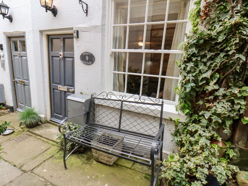 a black bench sitting outside of a house at Delft Cottage in Robin Hood's Bay