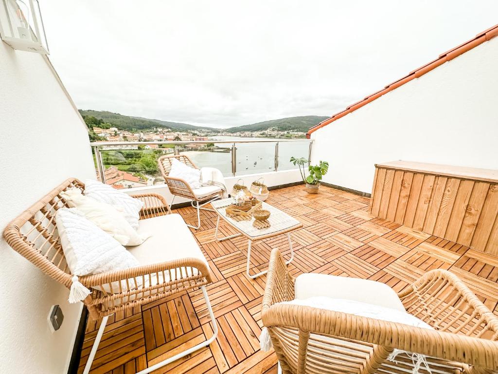 a balcony with wicker chairs and a table at El Olivo by ALÔGA in Corcubión