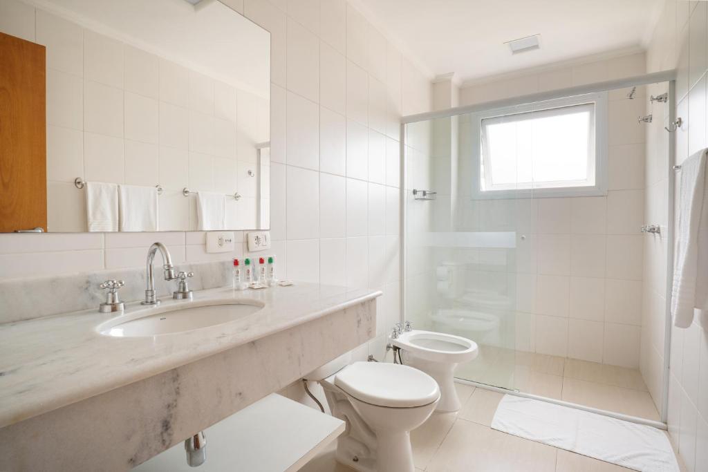 een witte badkamer met een wastafel en een toilet bij Pousada Itália Moderna in Campos do Jordão