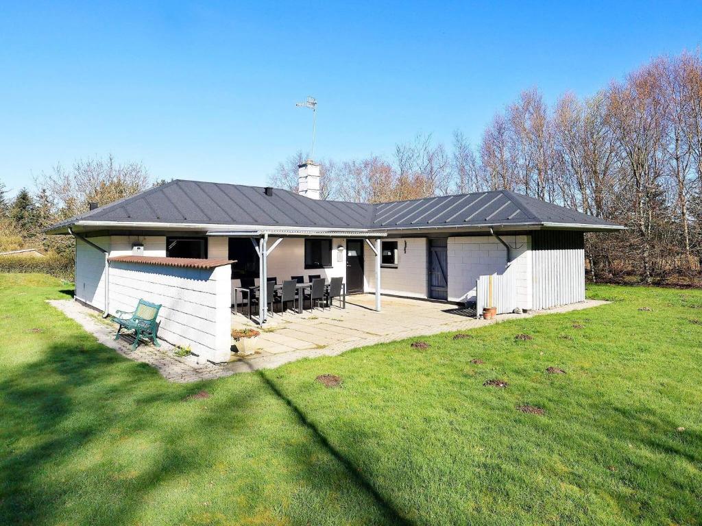 una casa blanca con techo negro y patio en Holiday home Vesløs IV en Øsløs