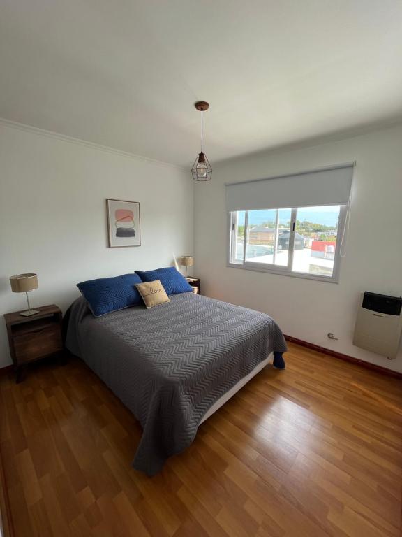 a bedroom with a bed with blue pillows and a window at Departamento moderno con balcon in Olavarría