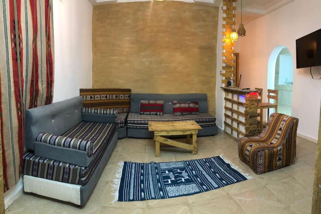 a living room with couches and a table and chairs at Dar Chahla in Tozeur