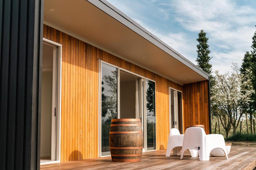 una casa con un barril y sillas blancas en una cubierta en Sublime Nooks en Havelock North